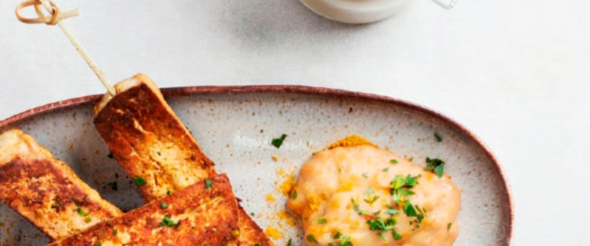 Grilované tofu tyčinky s omáčkou na talíři a sklenice s kořením