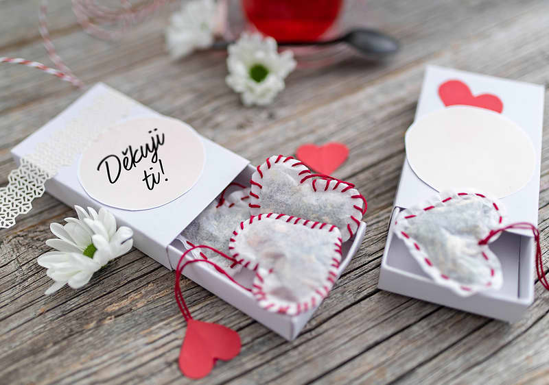 Dárková krabička s textem Děkuji ti a srdíčky na dřevěném stole, květiny kolem