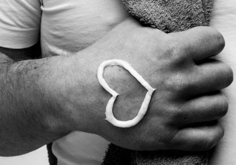 Ruka s krémem ve tvaru srdce na dlani, držící ručník