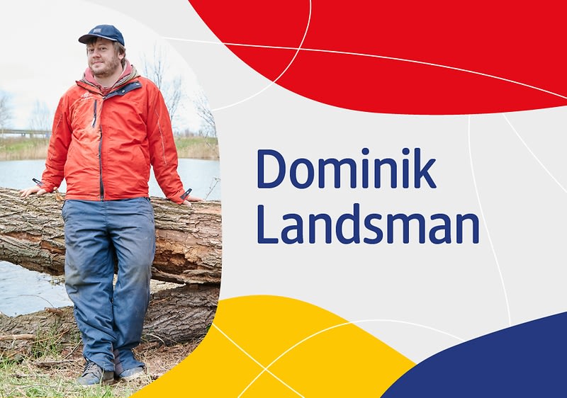 Muž v červené bundě stojící u stromu, text: Dominik Landsman