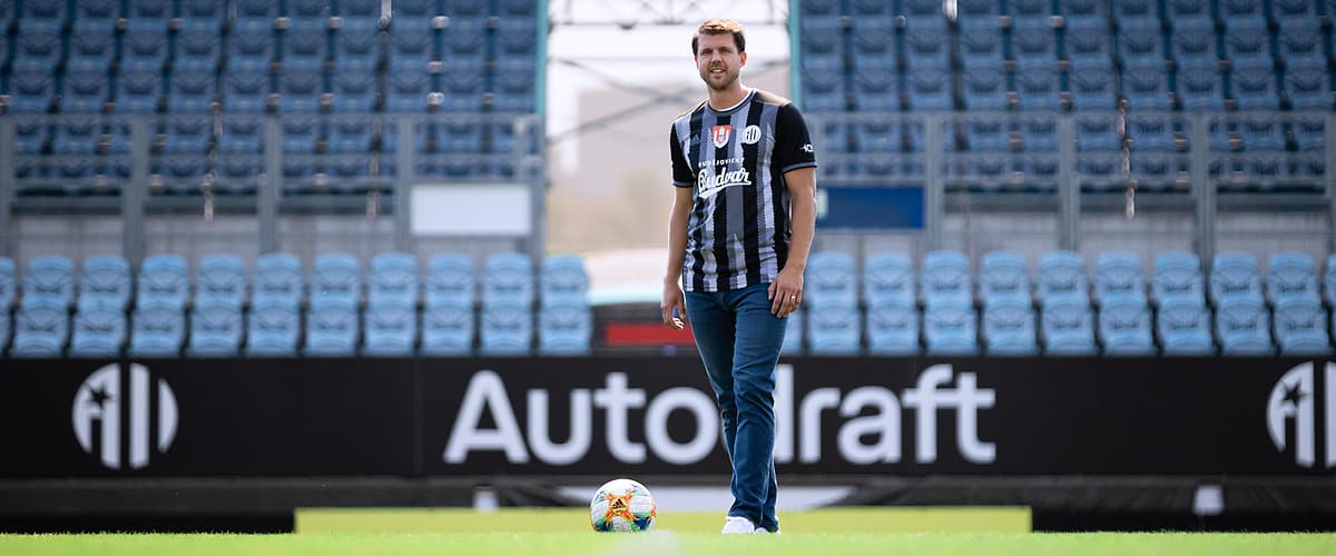 Fotbalista stojící na hřišti před prázdnými tribunami stadionu
