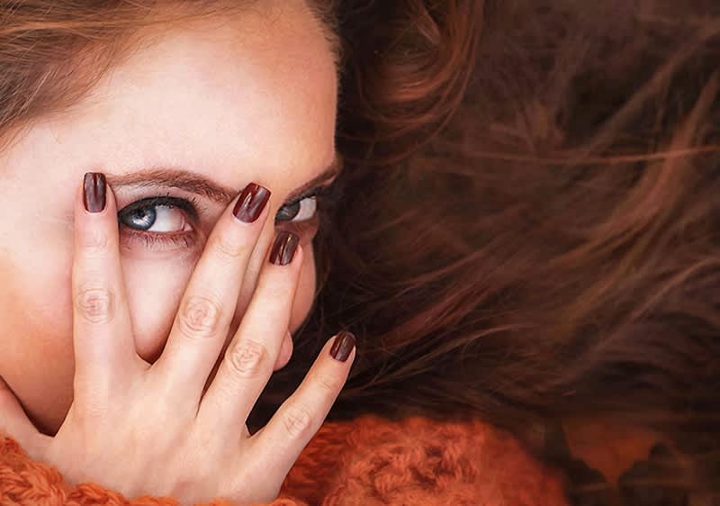 Žena s dlouhými hnědými vlasy a oranžovým svetrem