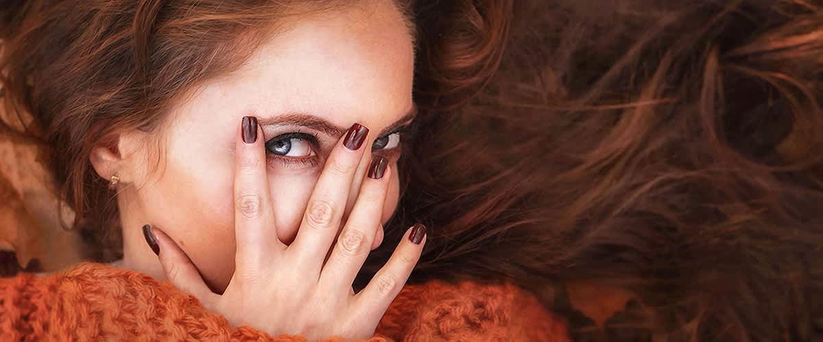 Žena s dlouhými hnědými vlasy a oranžovým svetrem