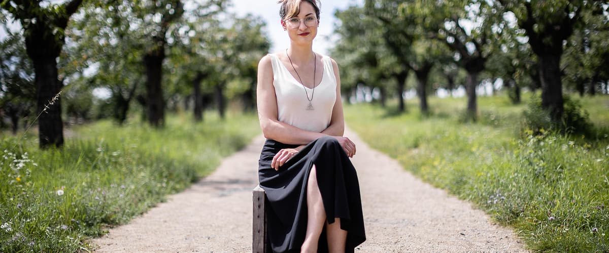 Žena sedící na cestě mezi stromy v přírodě