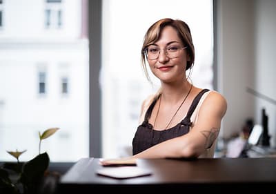 Žena sedící u stolu s rozmazaným obličejem, v pozadí okno a rostlina