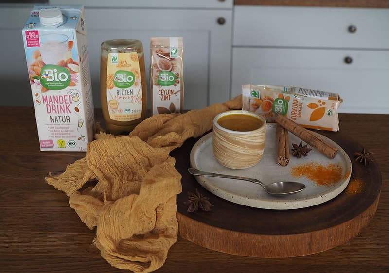 Bio mandlový nápoj, sušenky, koření, hrnek s nápojem na dřevěném podnosu v kuchyni