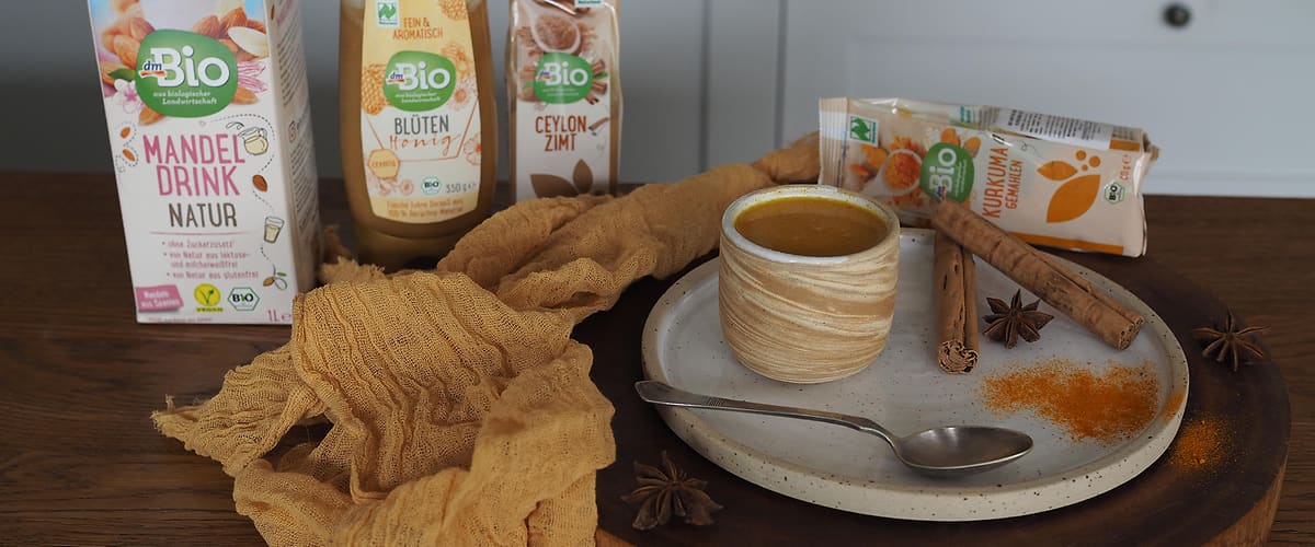 Bio mandlový nápoj, sušenky, koření, hrnek s nápojem na dřevěném podnosu v kuchyni