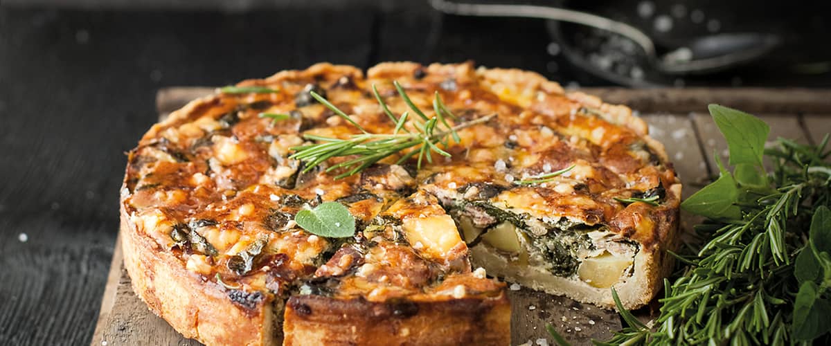 Slaný koláč s bylinkami na dřevěném prkénku