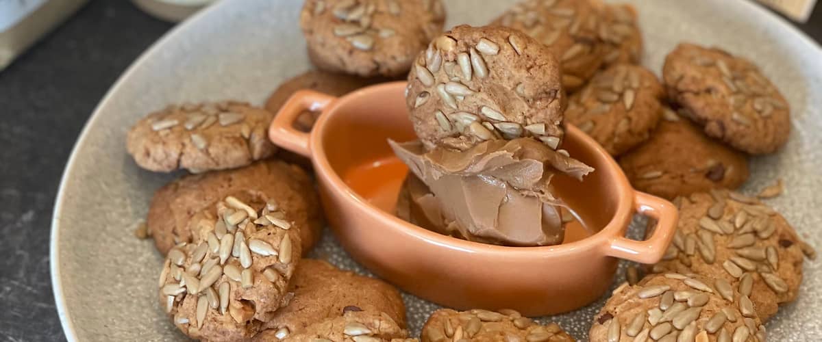 Sušenky s oříšky na talíři, obklopené ingrediencemi jako ořechové máslo a vejce