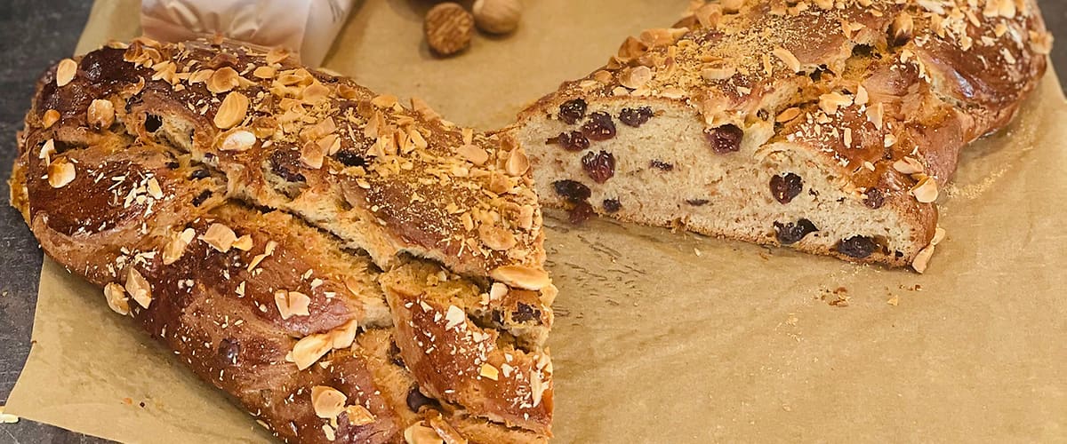 Domácí pečivo s rozinkami a ořechy na pečicím papíru, obklopené ingrediencemi jako vejce a mouka