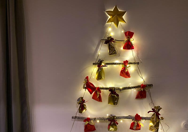 Vánoční dekorace na zdi ve tvaru stromku s dárky a světýlky