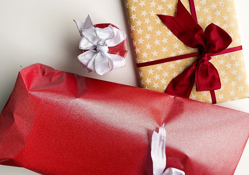 Tři dárky zabalené v červeném a zlatém papíru s mašlemi