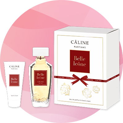 Eine Parfümflasche und eine Tube mit rotem Etikett „Belle Icône“ neben einer weißen Verpackung mit rotem Band und Rosenmuster.