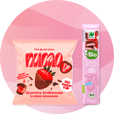 Eine Packung Nucao Crunchy Erdbeeren in Schokolade neben einem Bio-Schokoriegel mit Himbeer-Joghurt-Geschmack.