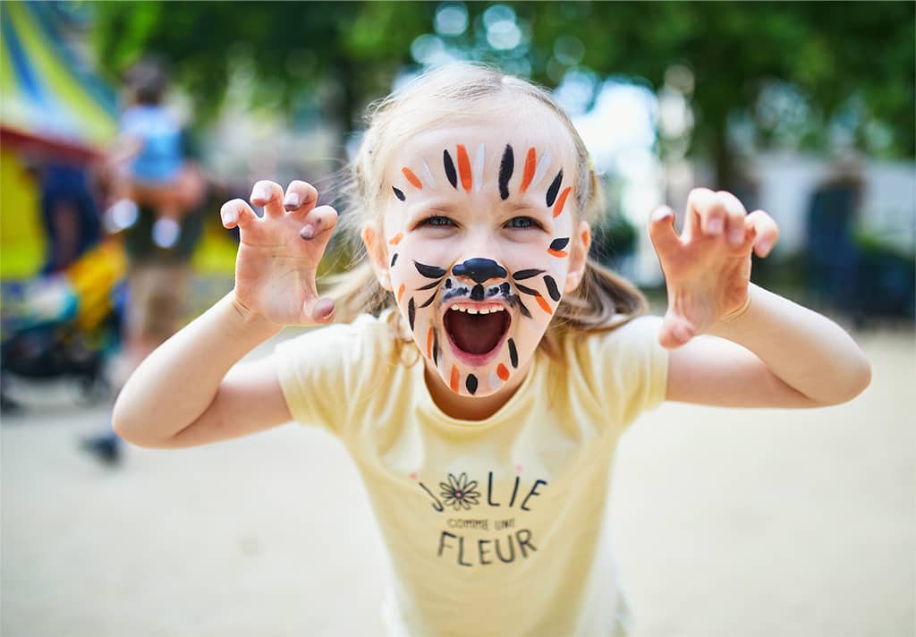 Kind spielt im Freien mit erhobenen Händen