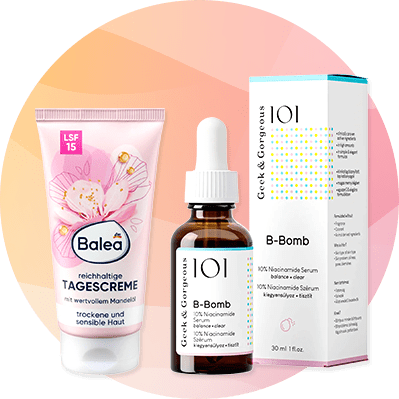 Links eine rosa Tube Balea reichhaltige Tagescreme mit Mandelöl und LSF 15 für trockene und sensible Haut, daneben eine braune Pipettenflasche mit weißem Etikett „101 Geek & Gorgeous B‑Bomb 10% Niacinamide Serum“ und rechts die passende weiße Verpackungsbox mit farbigen Punkten und Produktinformationen