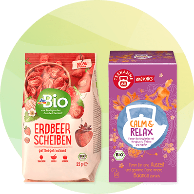 Zwei Bio-Produktverpackungen nebeneinander: links eine rosa Tüte „dmBio Erdbeer Scheiben gefriergetrocknet 25 g“ mit Erdbeerabbildungen, rechts eine violett-orange Schachtel „Teekanne Organic Calm & Relax“ mit Teetasse-Illustration und Blumenmotiv