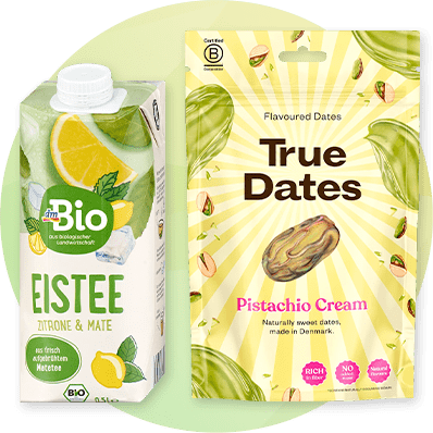 Links eine grüne Tetra Pak-Packung dmBio Eistee Zitrone & Mate, rechts eine gelbe Verpackung True Dates Pistachio Cream mit Dattelbild und Pistazienillustrationen