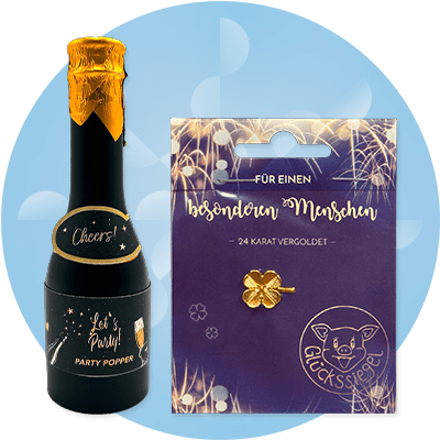 Eine schwarze Party-Popper-Flasche mit goldener Kappe und Aufschrift „Cheers! Let's Party!“ neben einer Verpackung mit goldener Kleeblatt-Pin und Text „Für einen besonderen Menschen“