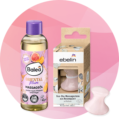 Eine Flasche Balea Massageöl mit der Aufschrift „Oriental Plum“ neben einer ebelin Verpackung für einen Gua-Sha-Massagestein aus Rosenquarz.