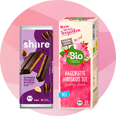 Eine lila Schokoladenverpackung von Share mit Nougat-Pralinen und eine dmBio Teepackung mit Hagebutte-Hibiskus-Tee.