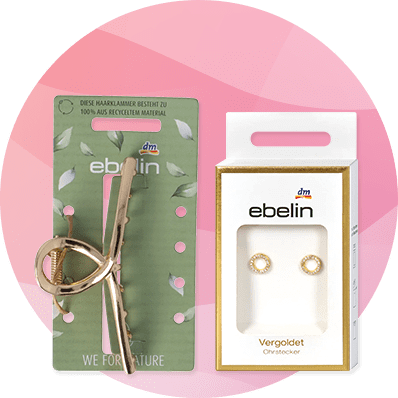 Eine goldene Haarklammer auf einer grünen Verpackung mit Blättern und der Aufschrift „ebelin“. Daneben eine weiße Verpackung mit goldenen Ohrsteckern und dem ebelin-Logo.