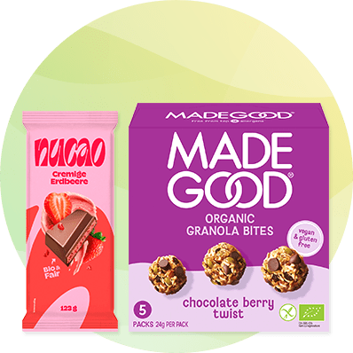Packung MADEGOOD Organic Granola Bites Chocolate Berry Twist in violett mit Produktabbildungen und Aufschrift „MADEGOOD ORGANIC GRANOLA BITES chocolate berry twist“, daneben pinke Schokoriegel-Verpackung „macao cremige Erdbeere 123 g“