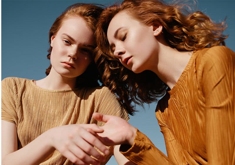 Zwei junge Frauen mit beigen Shirts und blauem Hintergrund