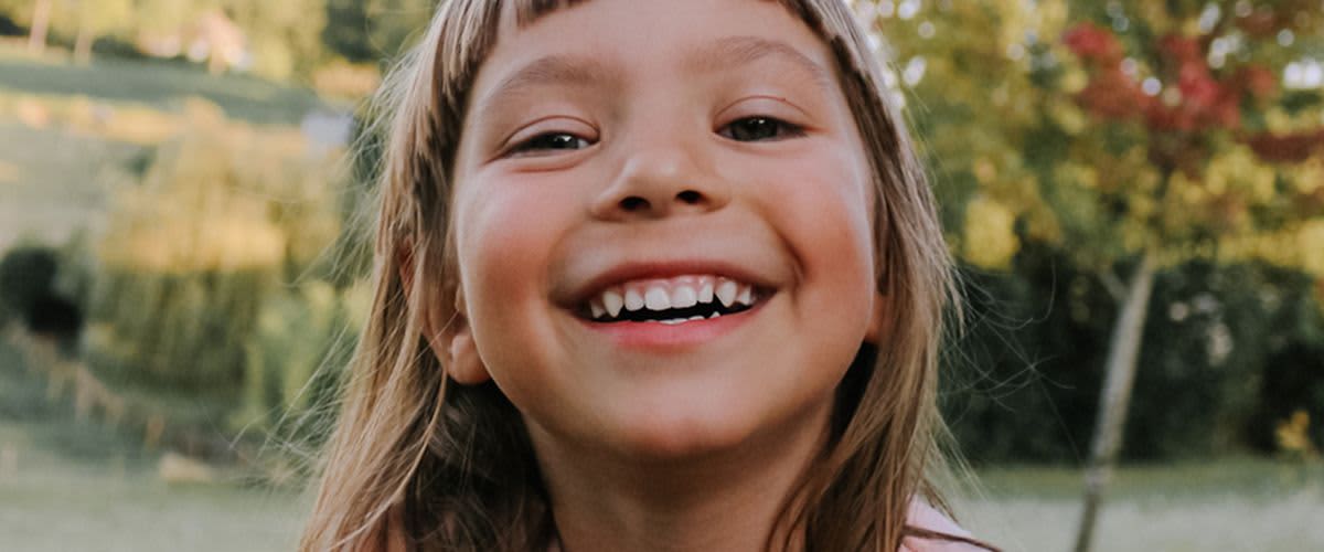 Kind im Freien mit grünem Hintergrund laechelnd