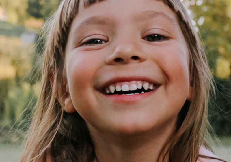 Kind im Freien mit grünem Hintergrund laechelnd