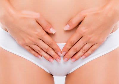 Frauenkörper in weißer Unterhose, beide Hände auf Blase