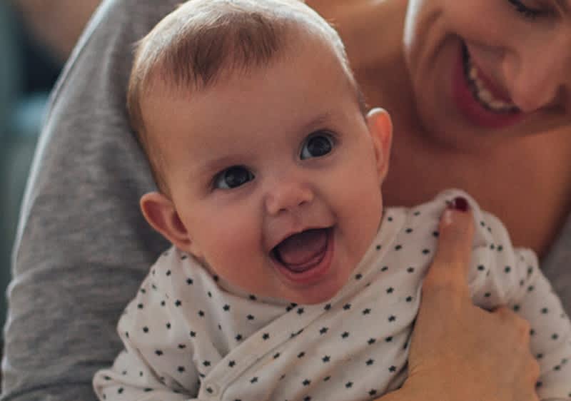 Lächelnde Mutter hält lachendes Baby im Arm