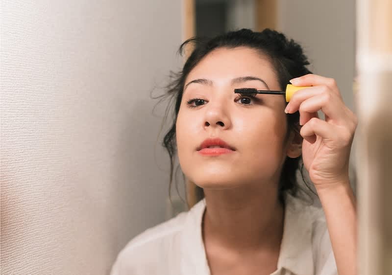 Frau schminkt Augen mit Mascara