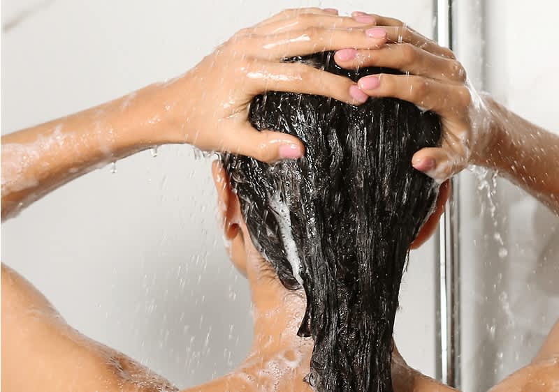 Frau wäscht sich die Haare
