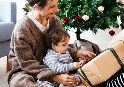 Mutter spielt mit Baby vor Weihnachtsbaum