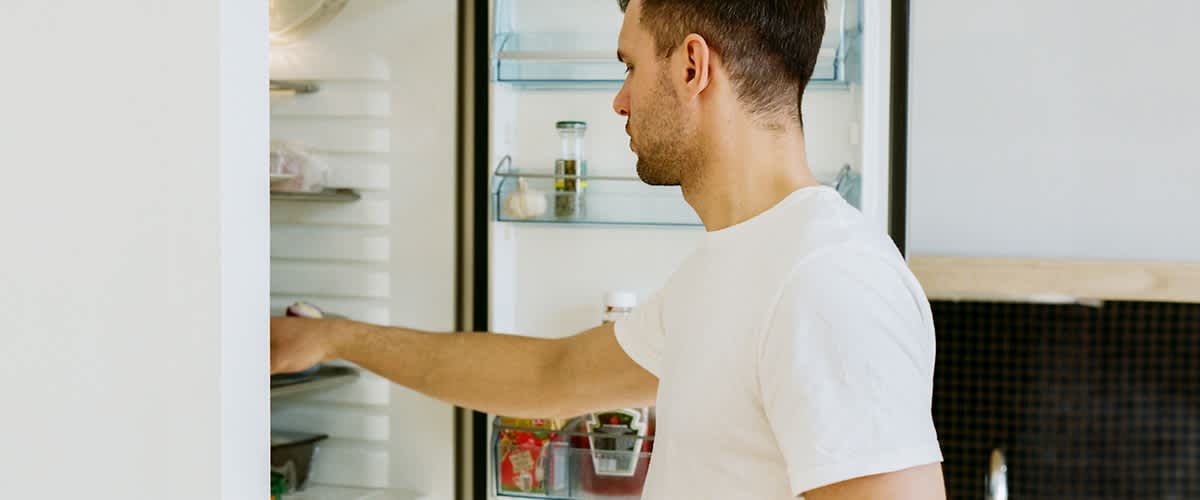 Mann holt etwas aus dem Kühlschrank