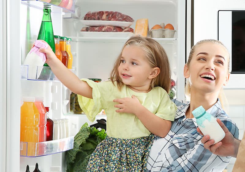 Familie vor Kühlschrank mit gesundem, ökologischem Einkauf