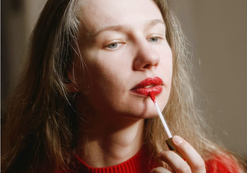 Frau schminkt rote volle Lippen
