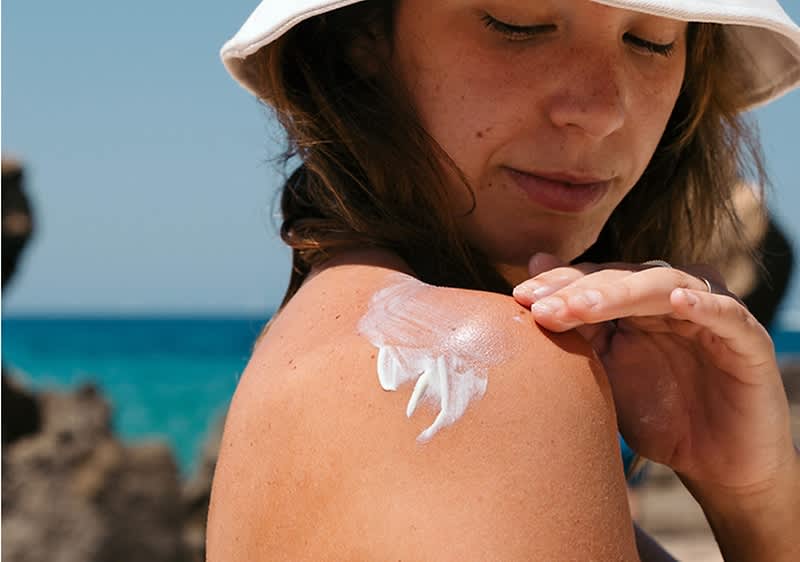 Frau cremt sich ein mit Sonnencreme