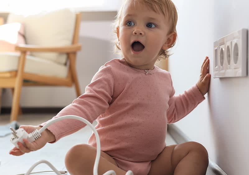 Kind greift zur Steckdose