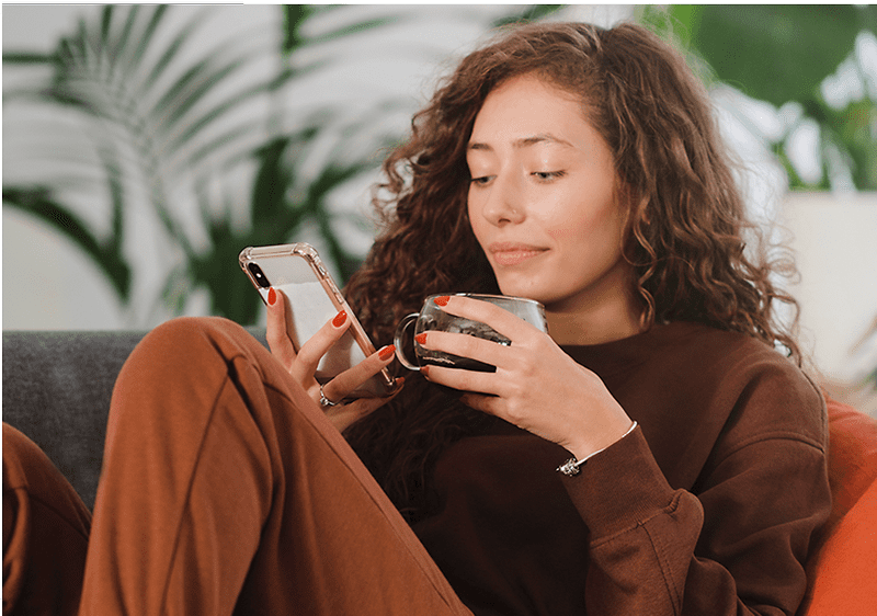 Frau sitzt mit Handy in der Hand auf der Couch