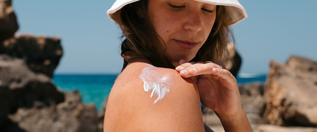 Frau cremt sich ein mit Sonnencreme