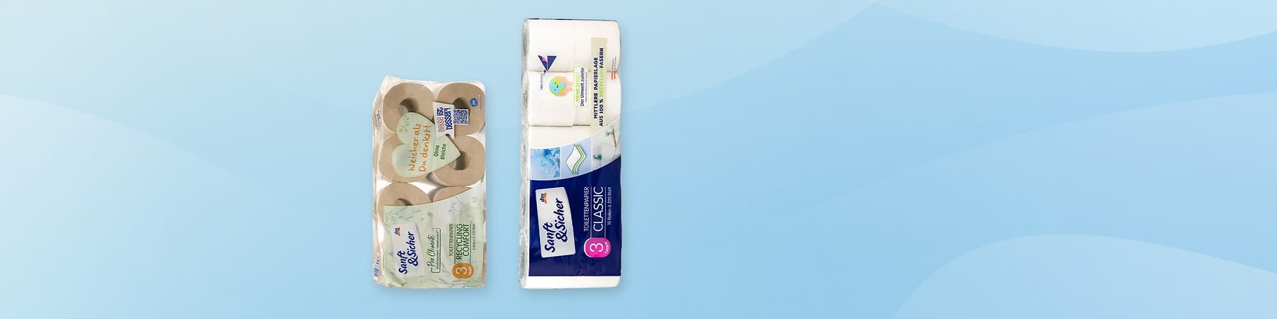 Zwei Packungen Toilettenpapier auf hellblauem Hintergrund; links eine 8er-Packung mit braunen Rollen und Aufkleber „Recycling Comfort“ sowie handschriftlicher Notiz „Vielleich Ol…“, rechts eine weiße 3er-Packung „Soft & Sicher CLASSIC“ mit blauem Etikett