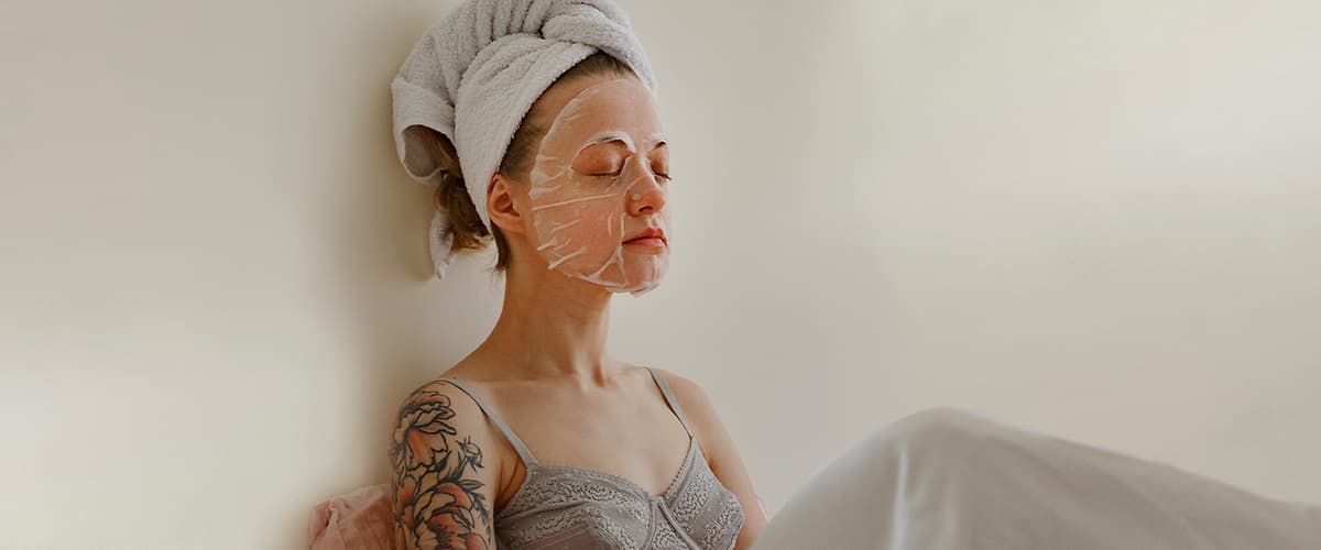 Frau mit Gesichtsmaske und Handtuch auf den Haaren