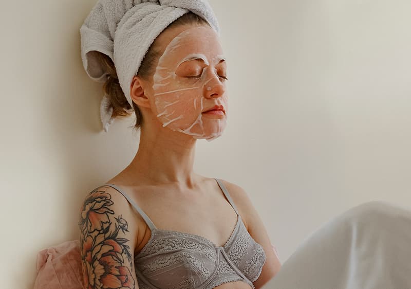 Frau mit Gesichtsmaske und Handtuch auf den Haaren