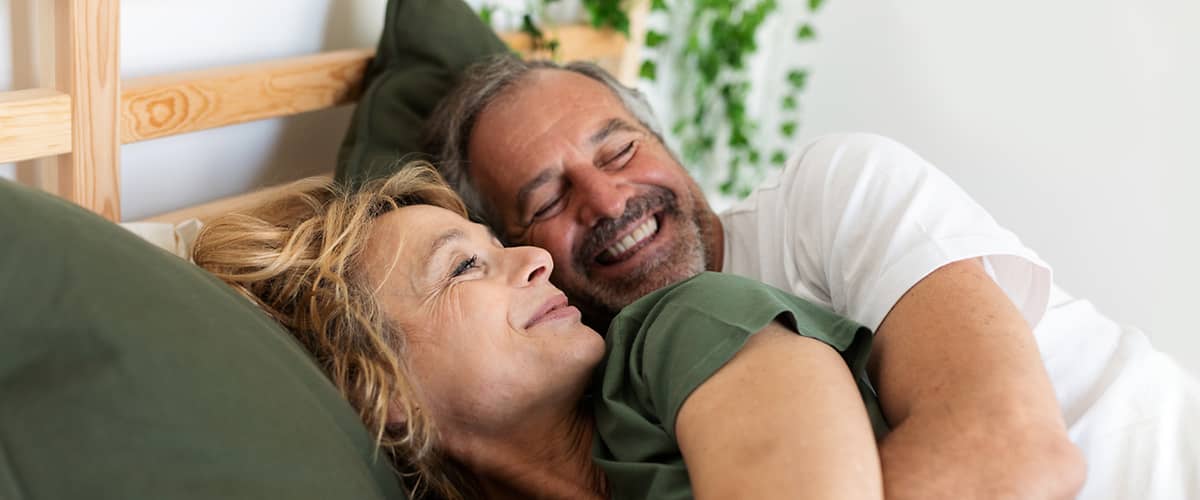Paar liegt kuschelnd im Bett