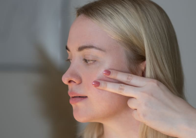 Blonde Frau beim Gesicht massieren mit zwei Fingern