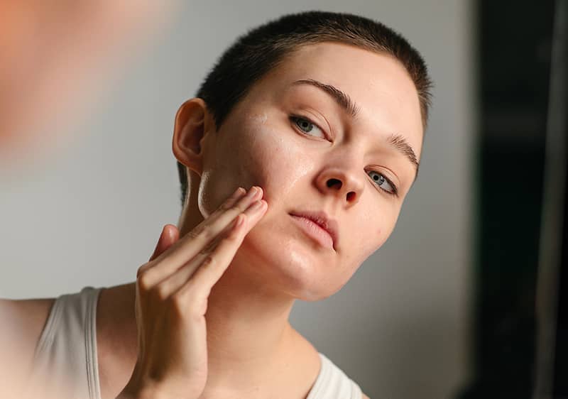 Frau cremt sich ihr Gesicht ein