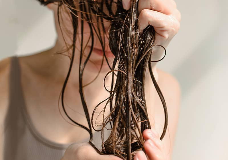 Frau hält ihr nasses Haar in der Hand