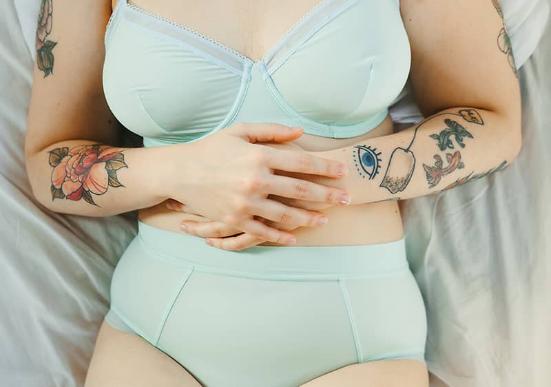 Frau in Unterwäsche hält ihren Bauch